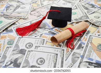 Miniature graduation cap on dollars bills. Student debt crisis