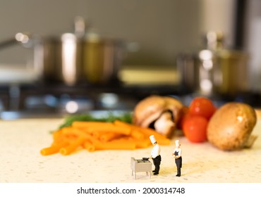 Miniature Head Chef Teaching Apprentice Chef In A Kitchen Background