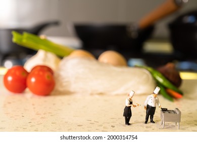 Miniature Head Chef Teaching Apprentice Chef In A Kitchen Background