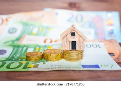 Miniature house model with coins stacks and euro banknotes on a wooden table, selective focus. Home loan concept. - Powered by Shutterstock