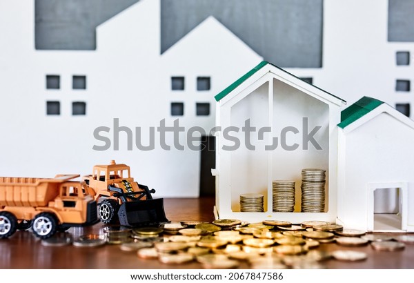 Miniature house\
models and construction truck models with glod coin on wooden\
table. Real estate developement or property investment.\
Construction industry business\
concept.
