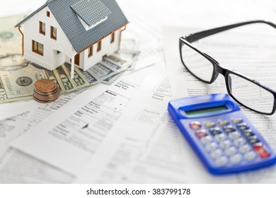 Miniature House With Money And Tax Forms.