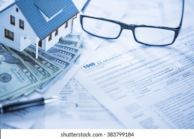 Miniature House With Money And Tax Forms.