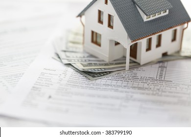 Miniature House With Money And Tax Forms.