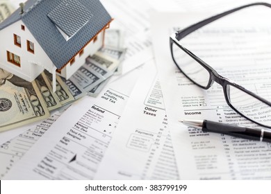 Miniature House With Money And Tax Forms.