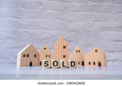 Miniature House And Wooden Blocks With The Word Sold On Marble Table.Real Estate Concept.Rent Apartment. Property. Rental, Renting Home. Buying. Purchase Housing