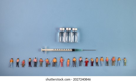 Miniature Human Figure Figurine Male Female Doll Row Line Vaccine Bottle Medical Injection Syringe Needle Border Copy Text Sign Space On Blue Paper Background