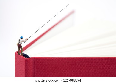 Miniature Man Fishing On A Book