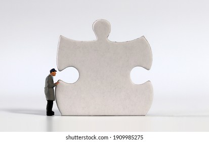 A miniature man with a puzzle piece.