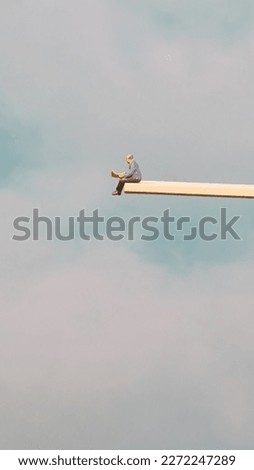 Miniature Man Reads Newspaper Perched on High Wooden Plank.