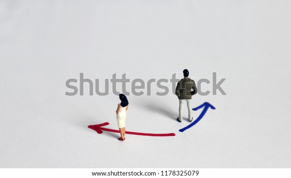 A
miniature man standing in front blue color direction with a
miniature woman standing in front red color
direction.