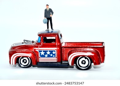 Miniature man standing on a toy truck in studio shot is concept for a political rally or speech with US American motif on the pickup roof as a politician might at an event - Powered by Shutterstock