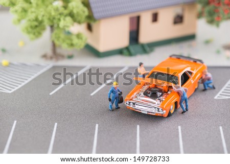 Miniature mechanics working on a car close up