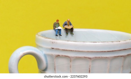 Miniature Men reading Newspapers atop Coffee Cup. - Shutterstock ID 2237602293