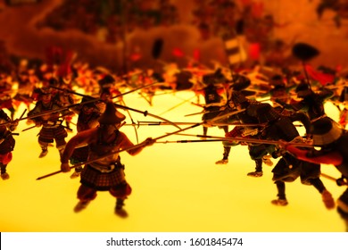 Miniature model figures depicting Siege of Osaka, battling Japanese samurai warriors with crossed naginata swords on poles weapons, macro close up