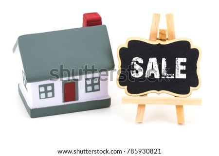 Miniature model of house and a Blackboard with text: sale.