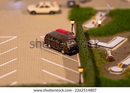 Miniature models of toy cars are parked in the parking lot for cars.