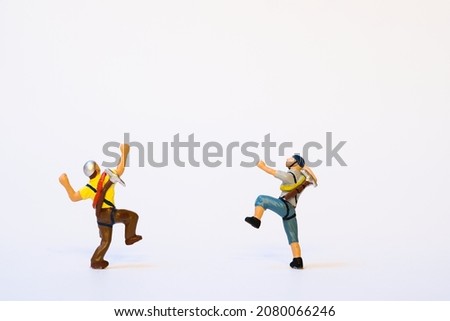 Miniature mountain climber in action, back view, white background, copy space