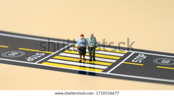 A miniature\
old couple crossing a\
crosswalk.