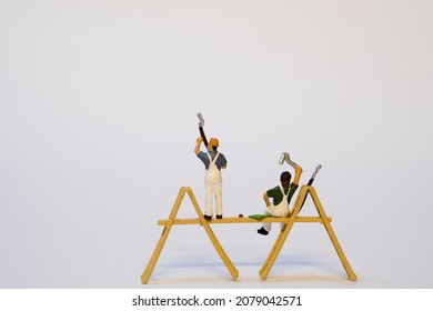 miniature painter on a wooden scaffold while working. white background, copy space - Shutterstock ID 2079042571