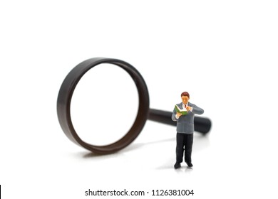 Miniature People: Businessman Reading Book With Magnifier. Education And Business Concept.