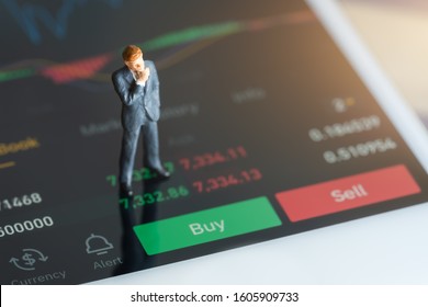 Miniature people: Businessman standing on mobile phone, chart, numbers and sell and buy options. red and green candlestick chart and stock trading smartphone screen background.