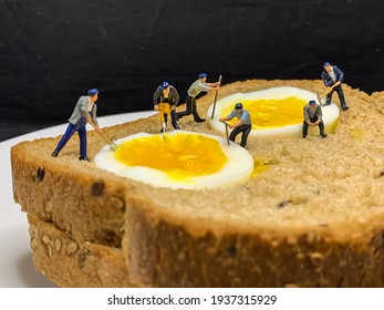 Miniature people - Concept photography. A team of construction workers works in a boiled egg on a piece of bread. Close-up - Powered by Shutterstock