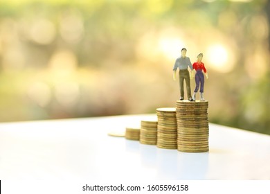 Miniature People: Couple Figure Walking On Top Of Stacked Coins , Planning For Saving Or Retirement Planning Concept.
