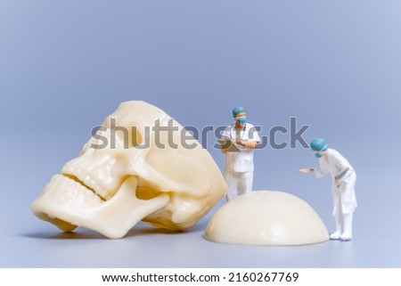 Miniature people Doctor with a giant human bone on a grey background, Science and Medical Concept