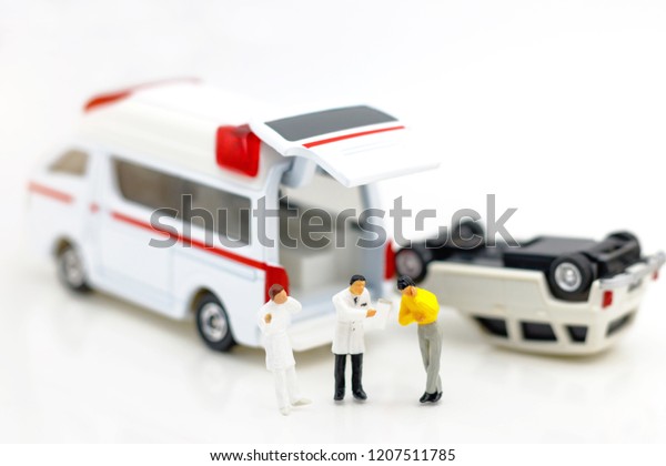 Miniature people: Doctor and patient\
standing with ambulance. Health care and emergency\
concept.