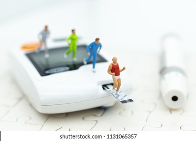 Miniature People Exercise Running On Glucose Meter With Lancet. Image Use For Medicine, Diabetes, Health Care Concept.