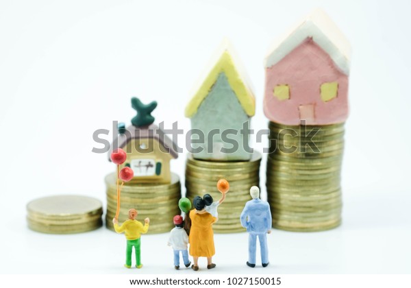 Miniature people: Family with balloon\
standing and seeing on an increasing stack of coins and lovely\
house use as family , children and financial\
concept.