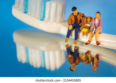 Miniature People Family Sitting on Dental Brush Blue Background