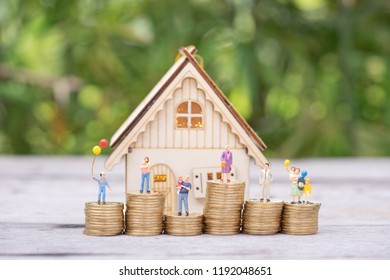 Miniature people: family standing on coins stacks with  house model on the top stack.  concepts. Concept for property ladder, mortgage,real estate investment, money, love and Valentine's day. - Shutterstock ID 1192048651