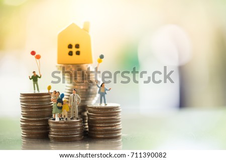 Miniature people: family standing on coins stacks with  house model on the top stack.  concepts. Concept for property ladder, mortgage,real estate investment, money, love and Valentine's day.