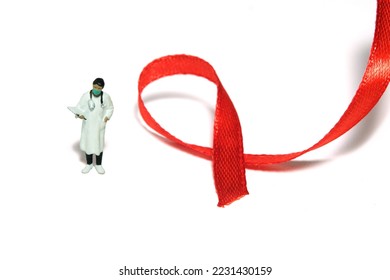 Miniature people figure toys photography. World AIDS Day awareness day concept. Girl woman doctor standing beside red ribbon. Isolated on white background. Image photo - Shutterstock ID 2231430159