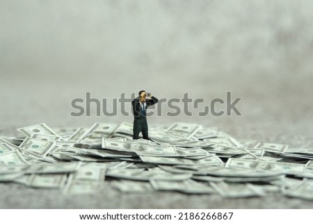 Miniature people figure toys photography. Inflation and recession concept. Businessmen standing above dollar money pile using binoculars searching for solution. Image photo