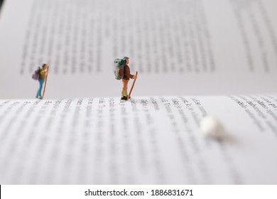 Miniature people, figures, hikers, traveling cross the book. Macro photography.