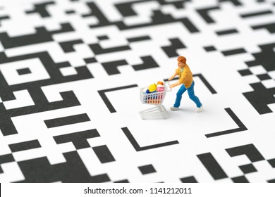 Miniature people figurine, a man with grocery in the shopping cart at the center of labyrinth QR code, ecommerce, consumer is mainly buy and sale in new innovation technology mobile channel.