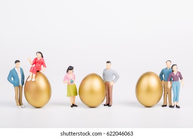 Miniature People With Gold Egg On White Background