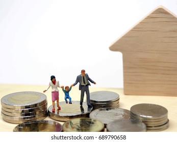 Miniature People Happy Family With Stack Coins On Table White Background Copy Space For Text : Saving Money, Insurance, Home Loan, Mortgage, Education And Real Estate Investment Concept.