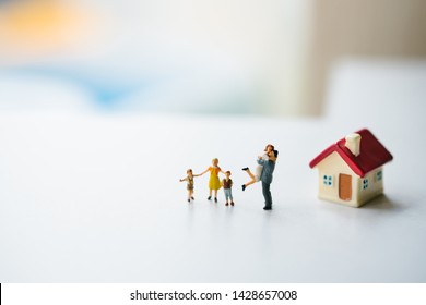 Miniature People, Happy Family Standing With Mini House Using As Family And Property Concept