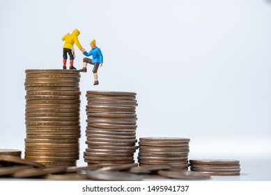 Miniature People Help Friend  Climbing On Stack Of Coins On White Background