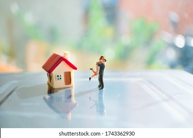 Miniature People, Lover Standing With Mini House On Sunlight Background Using As Family And Valentine's Day Concept