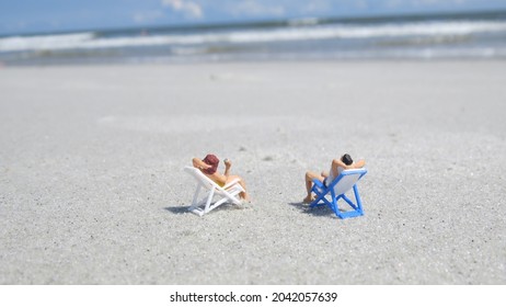 Miniature People lying in the Sun at Beautiful Beach - Shutterstock ID 2042057639