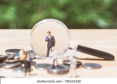 Miniature people: Magnifying glass focusing on the selected candidate on the coins stack, recruitment process, HR, HRM, HRD concepts.
