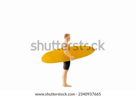 Miniature people man in a swimsuit, and holding a yellow surfboard, isolated on white background with clipping path