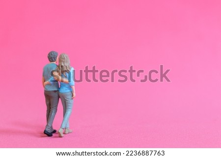 Miniature people man and woman in casual cloth standing together on pink background , Valentine's day concept