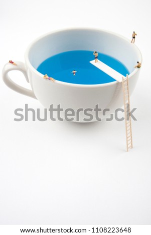 miniature people in mug cup swimming pool