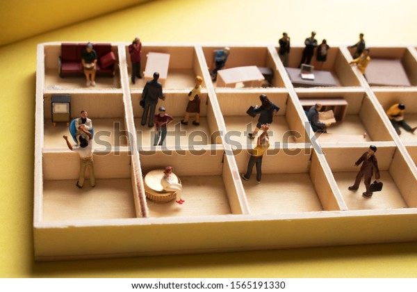 Miniature people in an office cubicle. Work\
in a sterile office environment. People separated in little boxes.\
Personal space to complete your work. Men and women in a white\
collar environment.